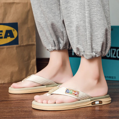 Person wearing beige sandals with a visible brand logo on a wooden floor.