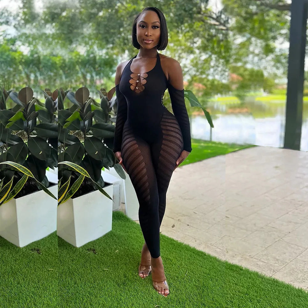 Woman in a black outfit standing outdoors with greenery and a path in the background