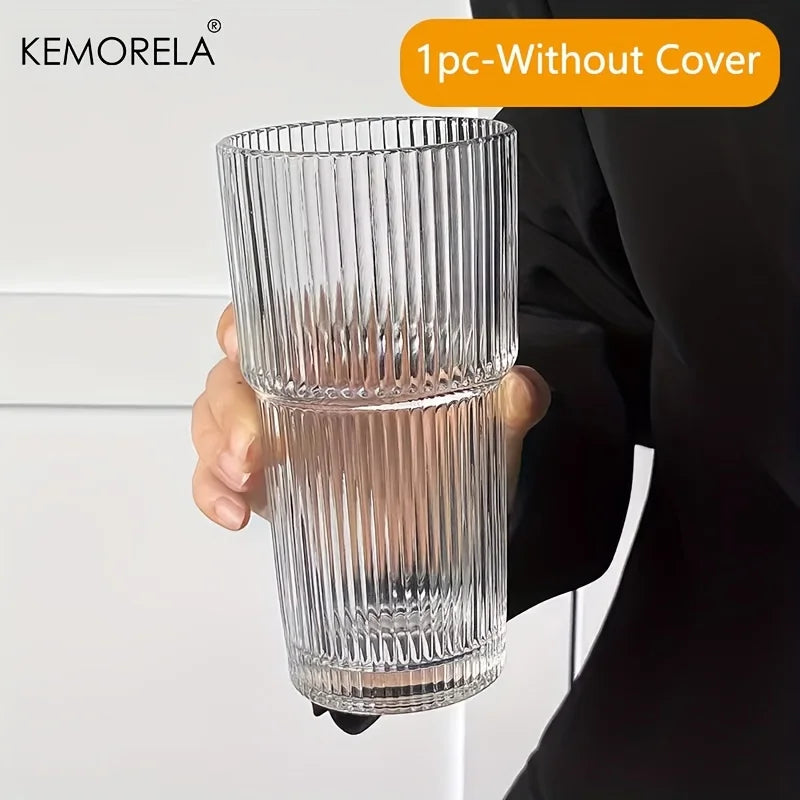 Clear ribbed glass vase held by a person with 'KEMORELA' branding above.
