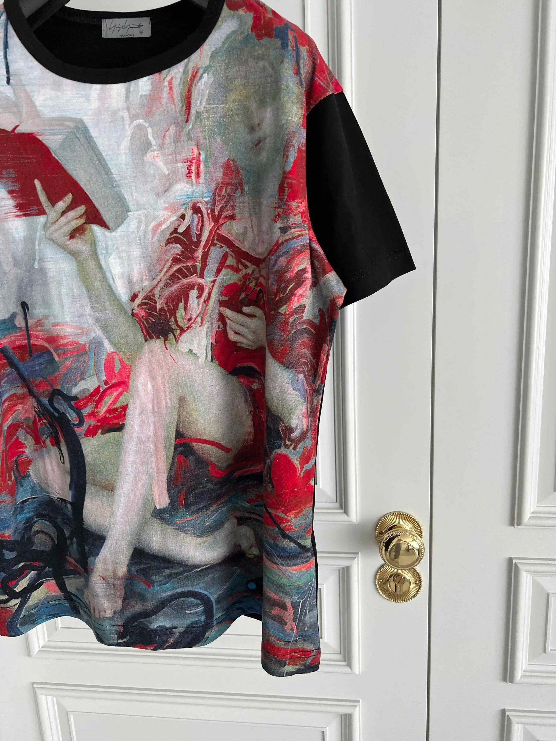 T-shirt with artistic design of a nude figure holding a book against a white door.