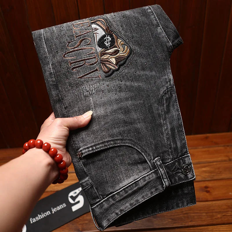 Black denim shorts with embroidery held by a hand on a wooden surface
