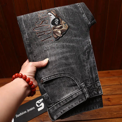 Black denim shorts with embroidery held by a hand on a wooden surface