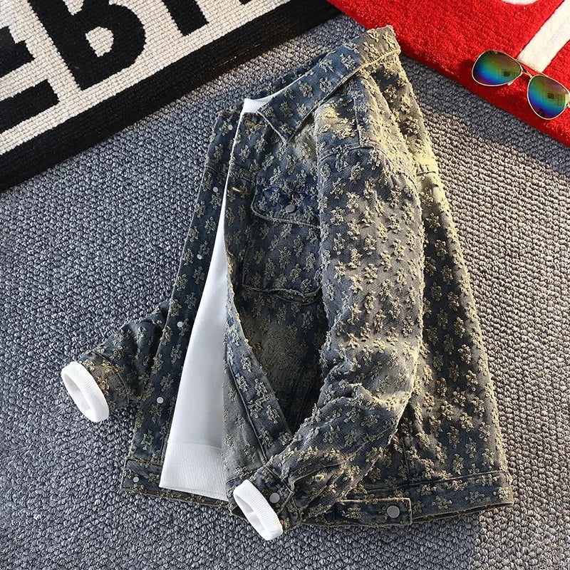 Distressed denim jacket on a textured surface with sunglasses and a red object in the background.