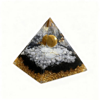 Pyramid-shaped object with a gold ball and white stones on a white background