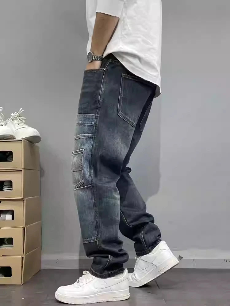 Person wearing dark blue baggy jeans and white sneakers against a gray background