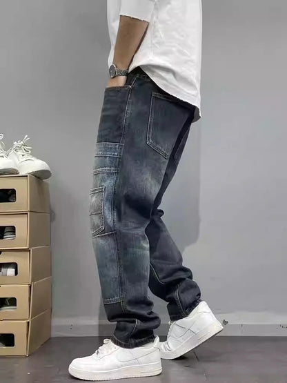 Person wearing dark blue baggy jeans and white sneakers against a gray background