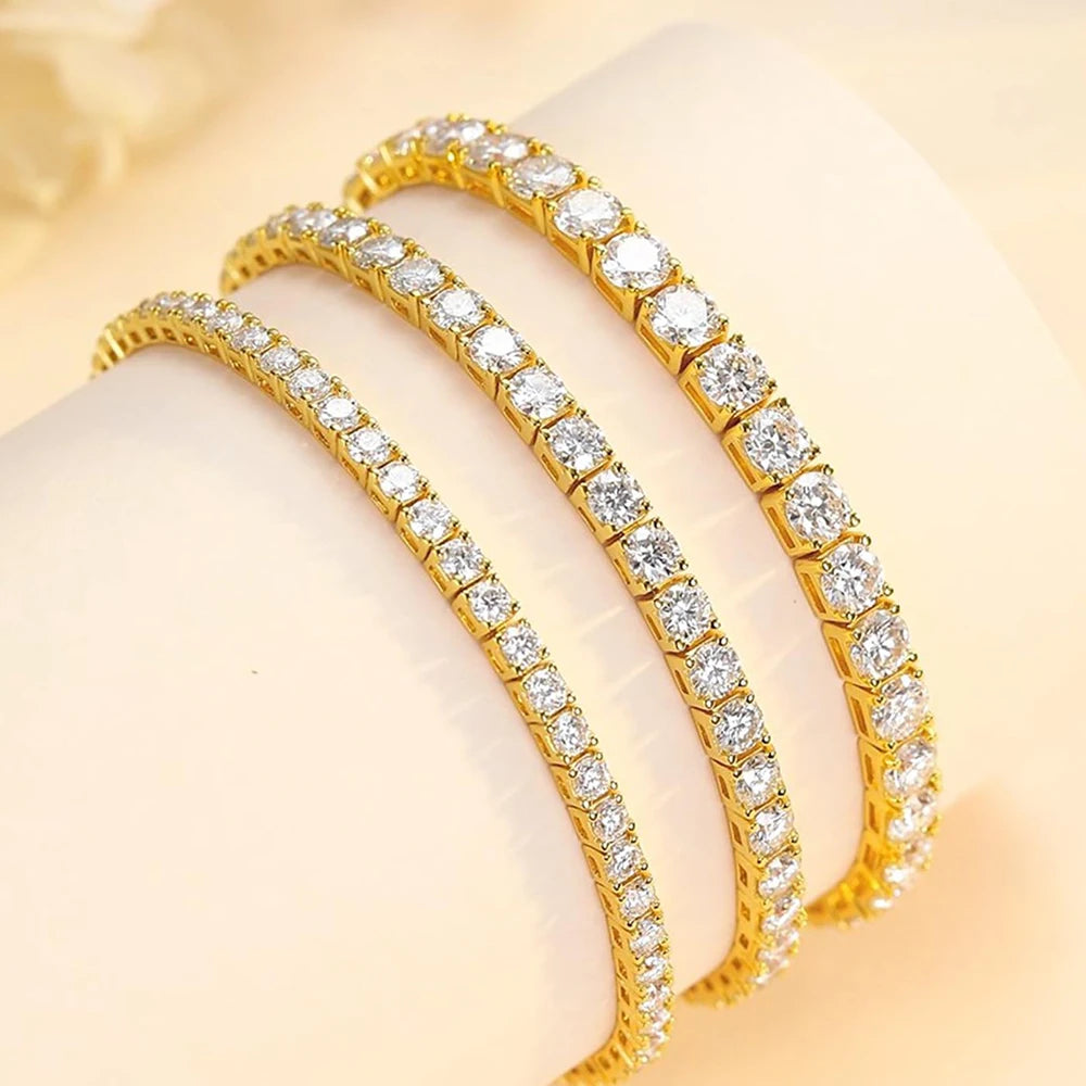 Two gold bracelets with clear gemstones on a beige background