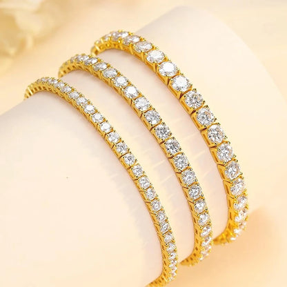Two gold bracelets with clear gemstones on a beige background