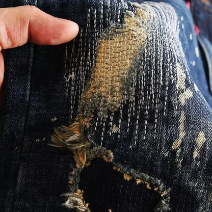 Close-up of a distressed denim fabric with a hand holding it.