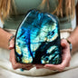 Person holding a large labradorite crystal with colorful patterns