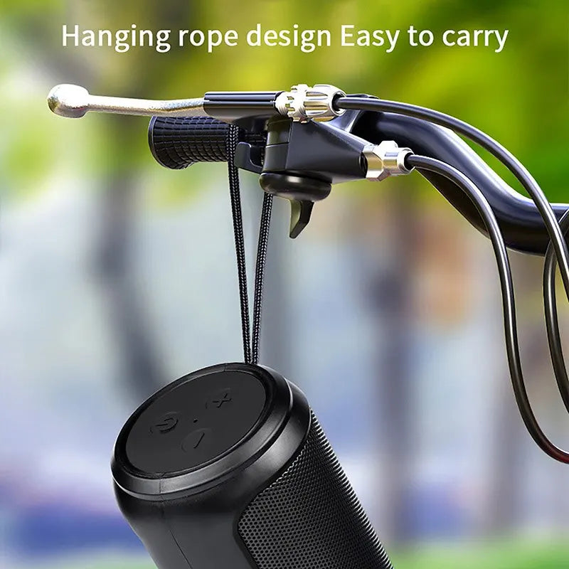 Black portable speaker with hanging rope design against a blurred green background