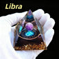 Pyramid-shaped object with a purple sphere and 'Libra' text, held by a gloved hand against a black background.