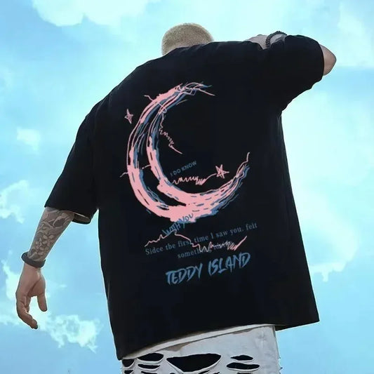 Person wearing a black t-shirt with a pink and blue design, standing against a blue sky.