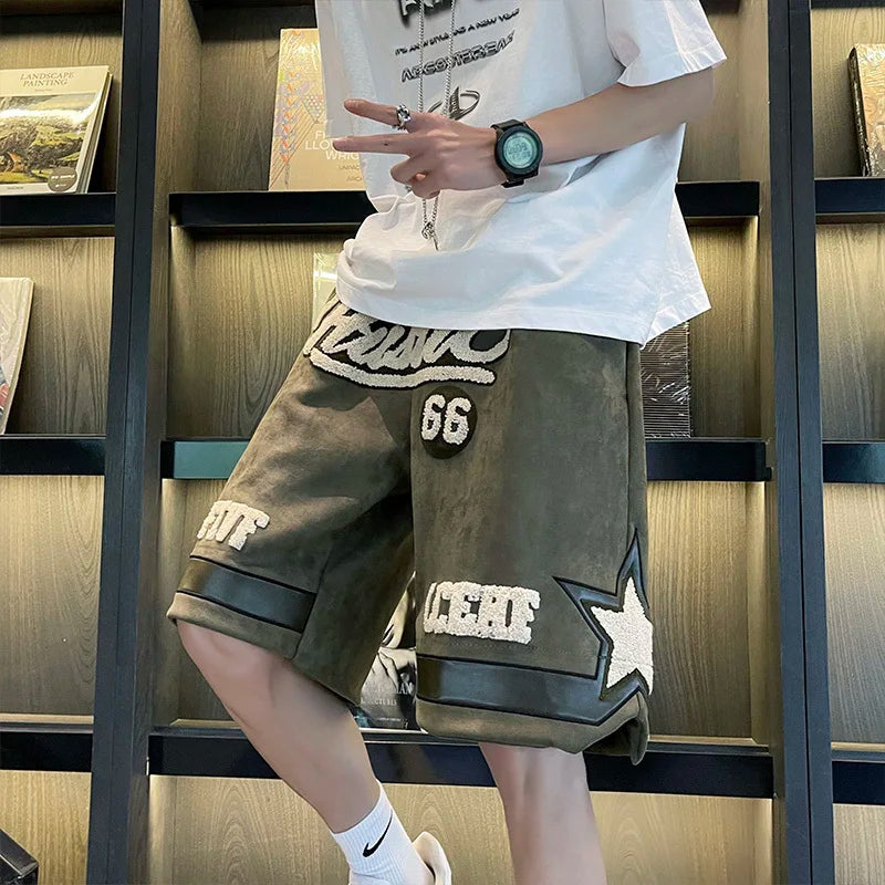 Person wearing a white t-shirt and brown shorts with star design in front of a bookshelf.
