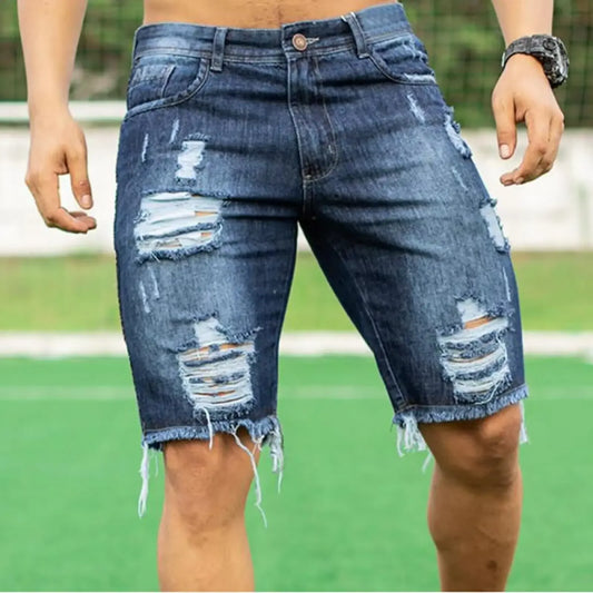 Distressed blue denim shorts worn by a person on a grassy field.