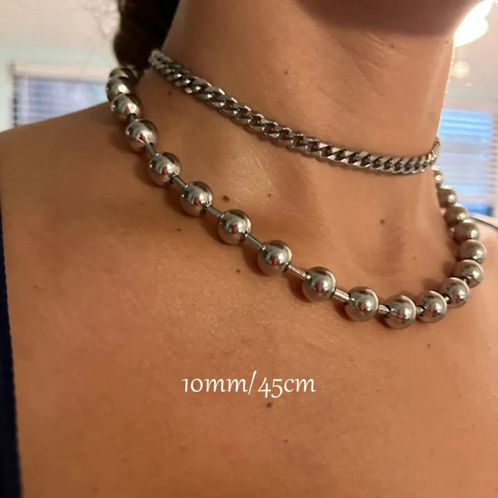 Close-up of a person wearing two silver necklaces with a blurred background