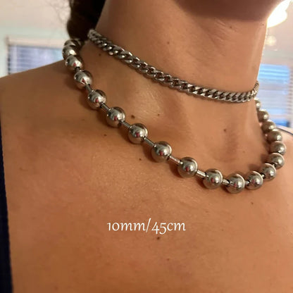 Close-up of a person wearing two silver necklaces with a blurred background