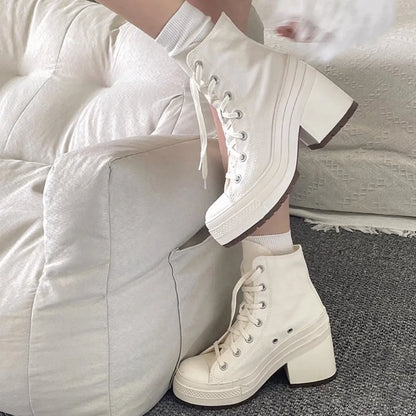 White high-top sneakers worn with white socks on a neutral background