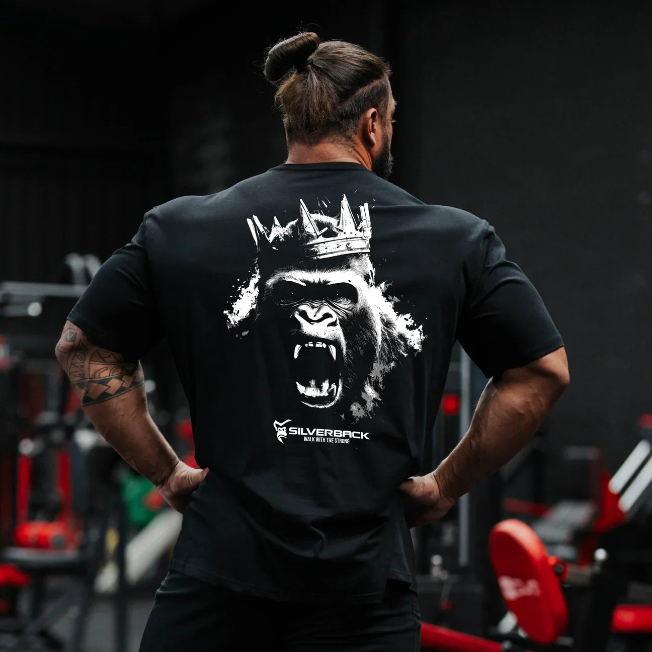 Person wearing a black t-shirt with a graphic design on the back in a gym setting