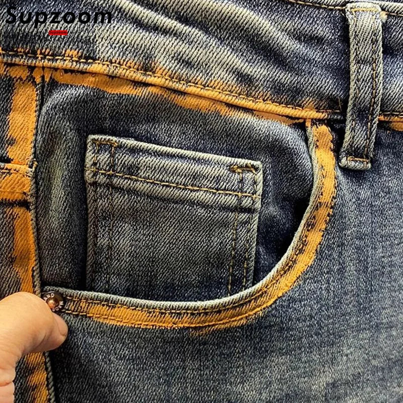 Close-up of a pocket on a pair of blue jeans with yellow stitching.