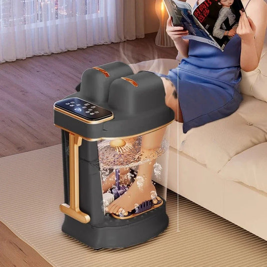 Foot spa device with water and stones on a mat, person reading a book on a couch.