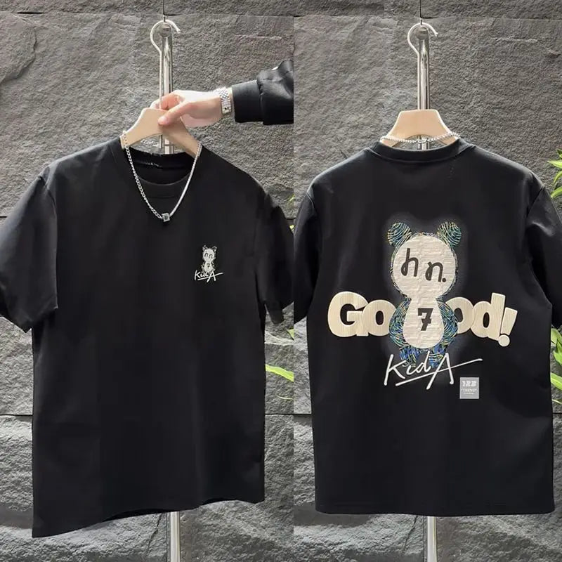 Two black t-shirts with different designs on hangers against a stone wall.