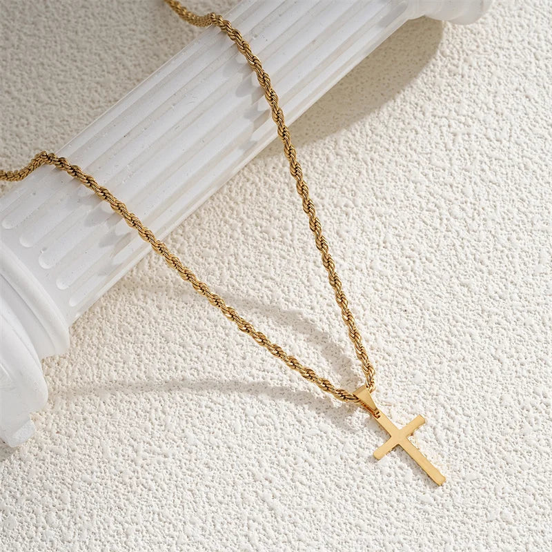 Gold chain necklace with a cross pendant on a white surface