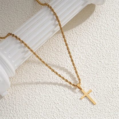 Gold chain necklace with a cross pendant on a white surface