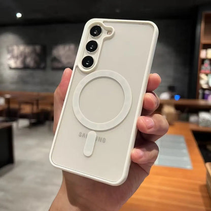 Hand holding a white phone case with a magnetic ring feature, blurred indoor background