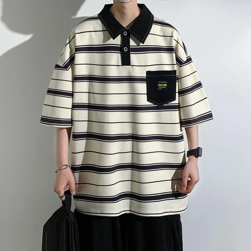 Person wearing a black and white striped polo shirt with a pocket against a plain background