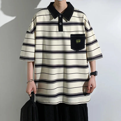 Person wearing a black and white striped polo shirt with a pocket against a plain background
