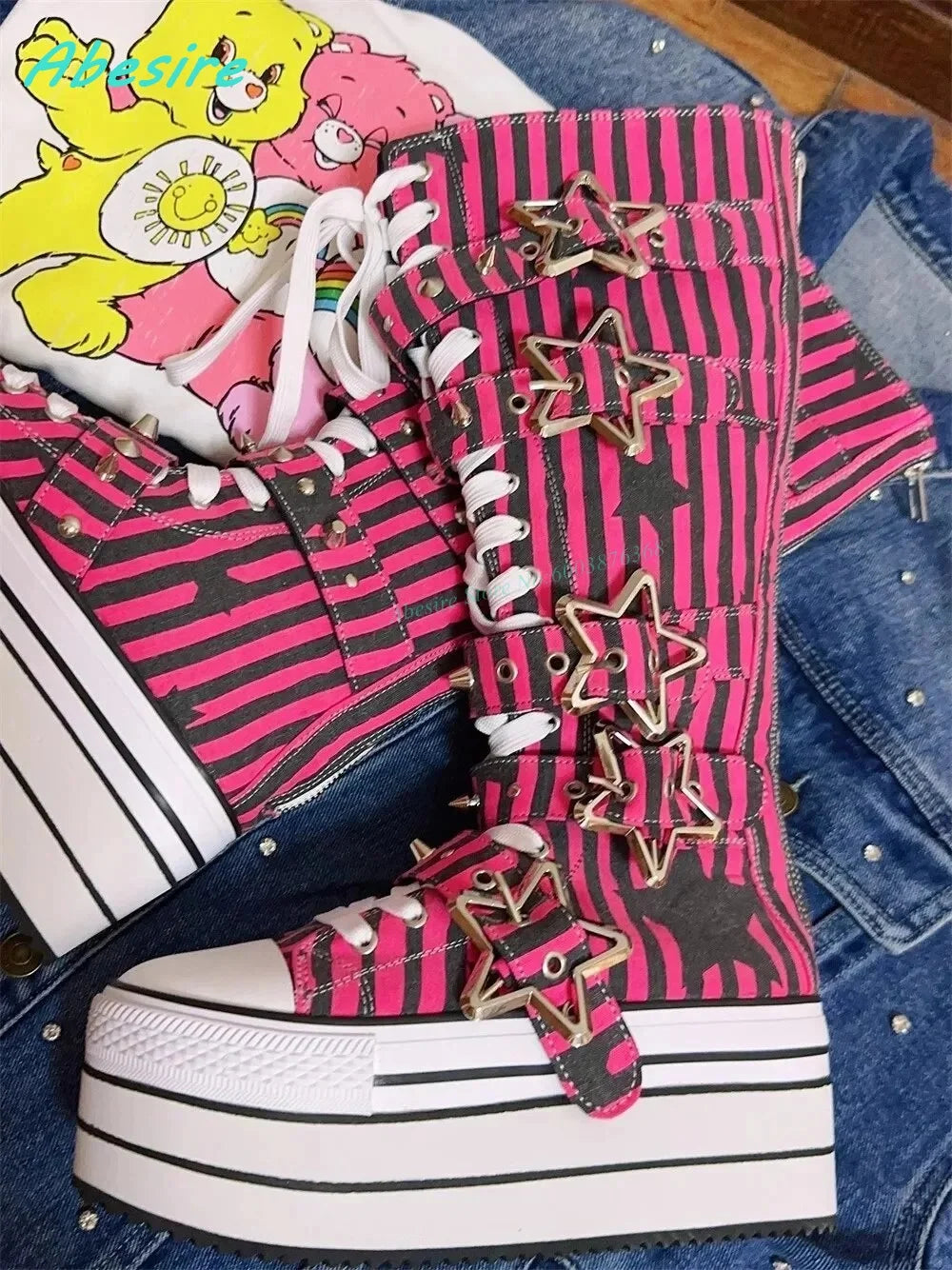 Pink and black striped high-top sneakers with star embellishments on a denim surface.