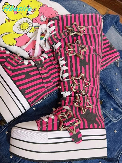 Pink and black striped high-top sneakers with star embellishments on a denim surface.
