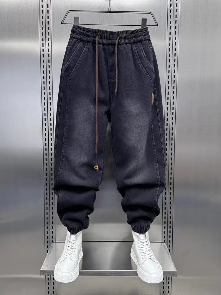 Dark blue jogger pants on a hanger against a metallic background