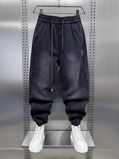 Dark blue jogger pants on a hanger against a metallic background