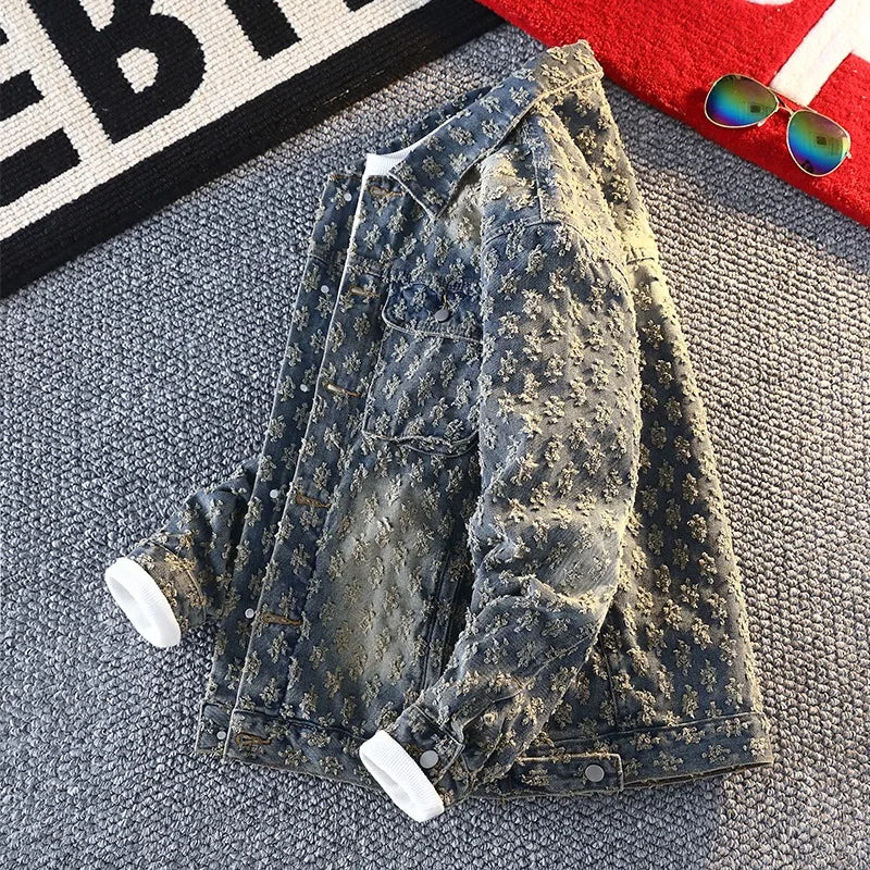 Distressed denim jacket on a textured surface with sunglasses and a red object in the background.