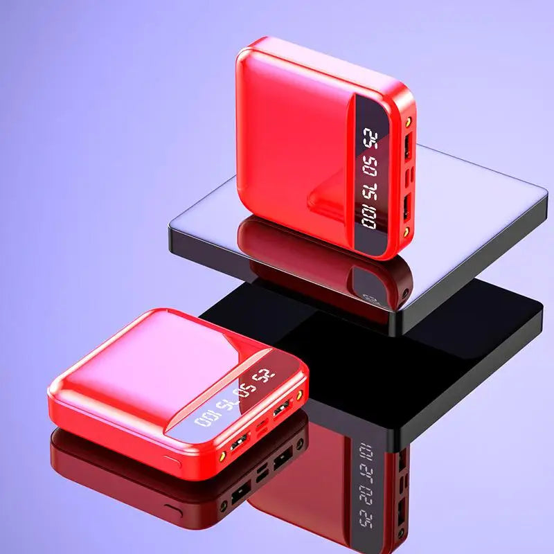Two red power banks with digital displays on a reflective surface with a purple gradient background.