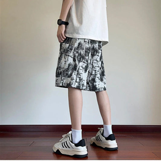 Person wearing a patterned skirt and sneakers on a plain background