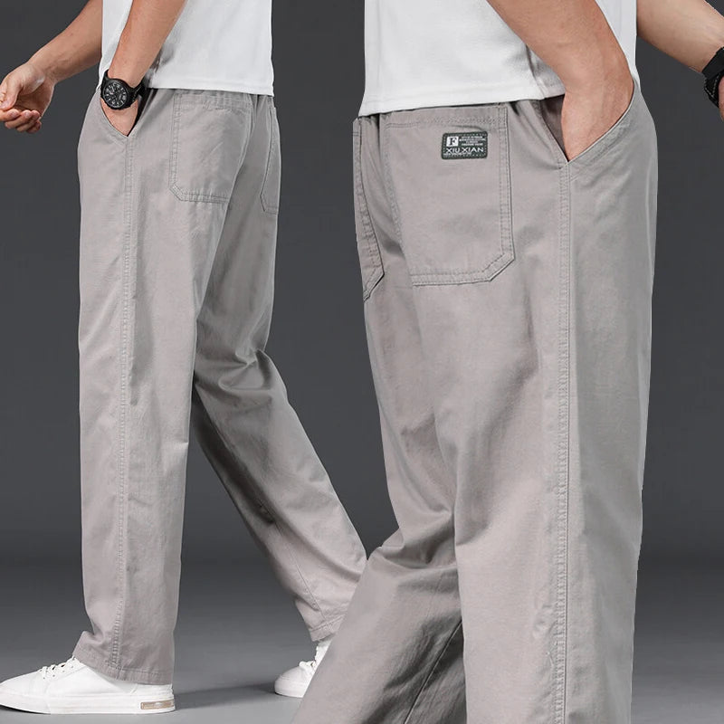 Gray pants with a brand label worn by a person on a dark background