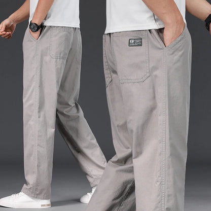 Gray pants with a brand label worn by a person on a dark background