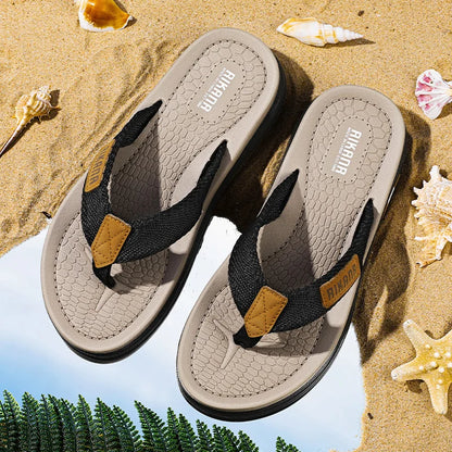 Pair of sandals with 'Birkenstock' branding on a sandy background with shells and plants.