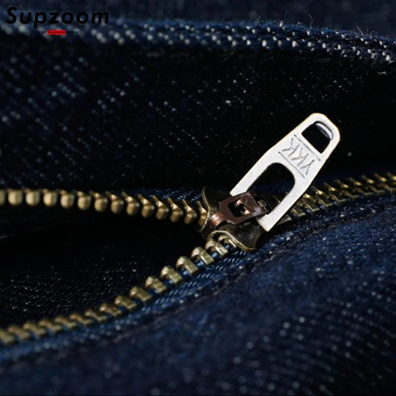 Close-up of a zipper on blue denim fabric with 'Supzoom' branding.
