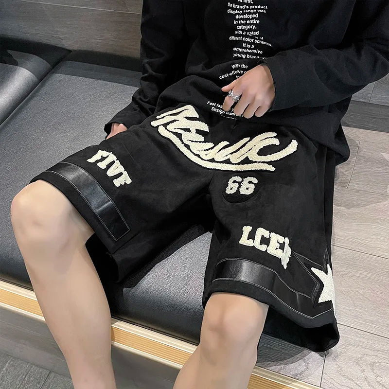 Person wearing black shorts with white text and graphics, sitting on a gray couch.