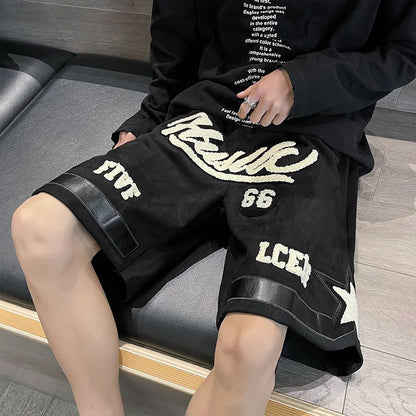 Person wearing black shorts with white text and graphics, sitting on a gray couch.