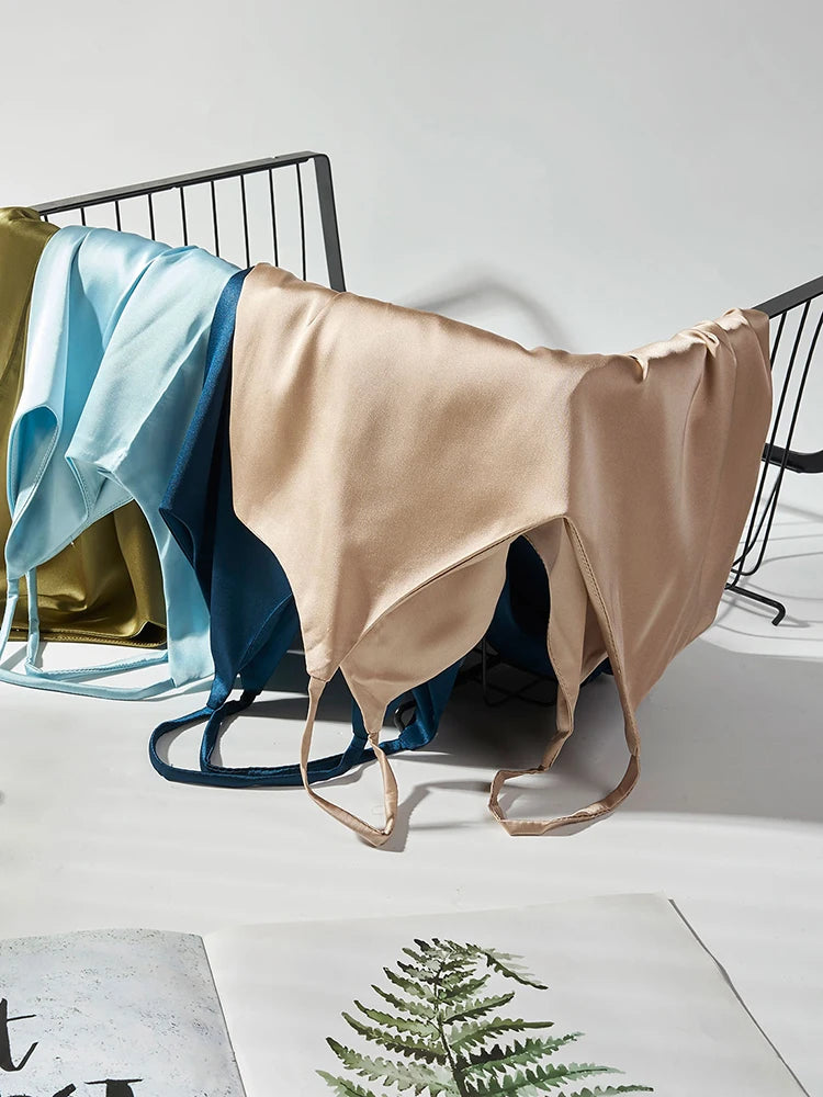 Beige satin sheet draped over a black metal bed frame with a white background.