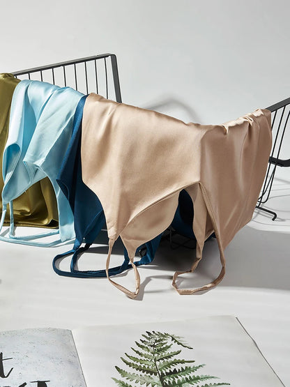 Beige satin sheet draped over a black metal bed frame with a white background.