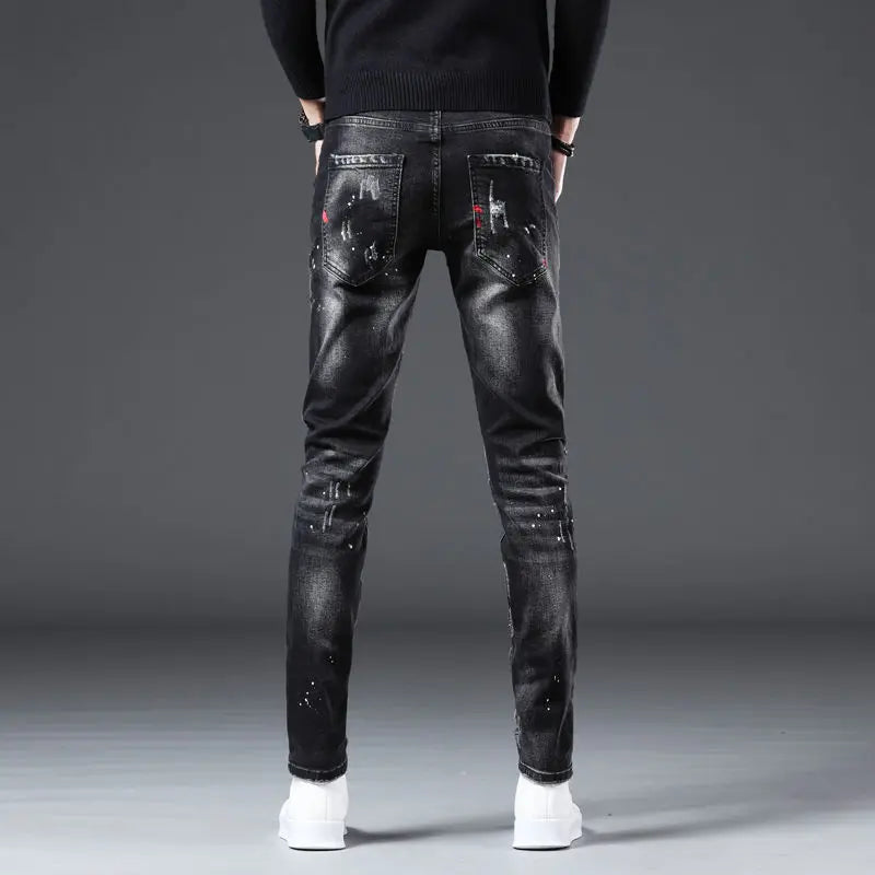 Black distressed jeans worn by a person on a gray background