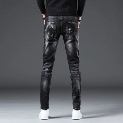 Black distressed jeans worn by a person on a gray background