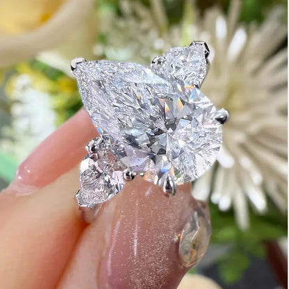 Diamond ring held by a hand with a blurred floral background