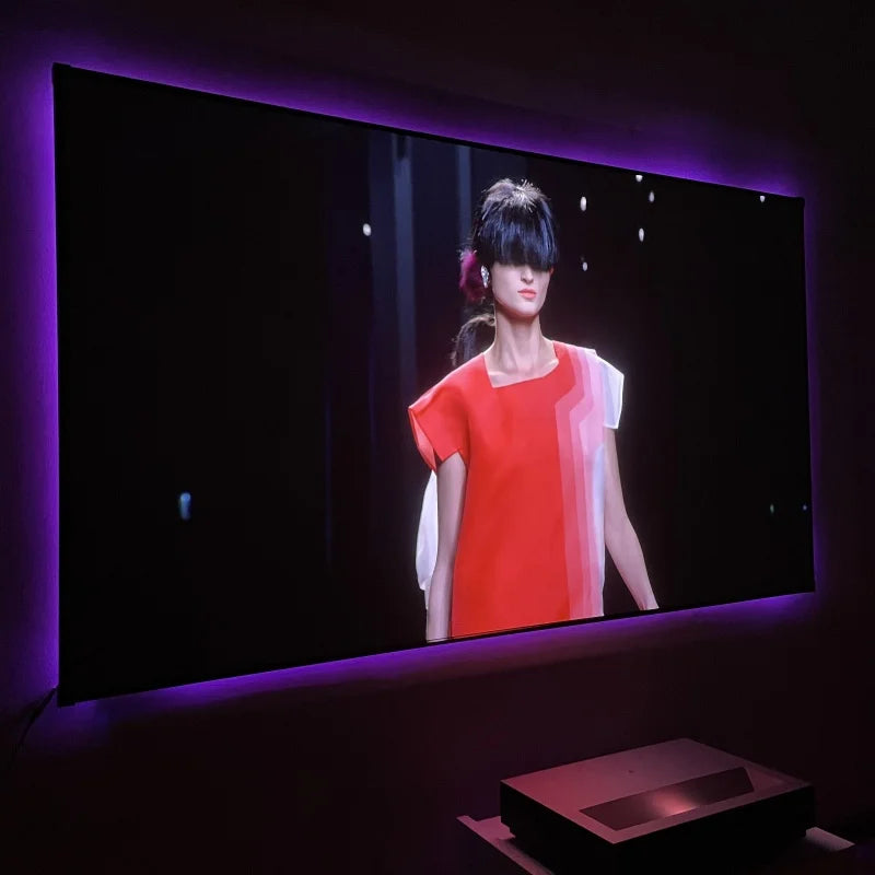 Large screen displaying a woman in a red dress with a projector below in a dark room.